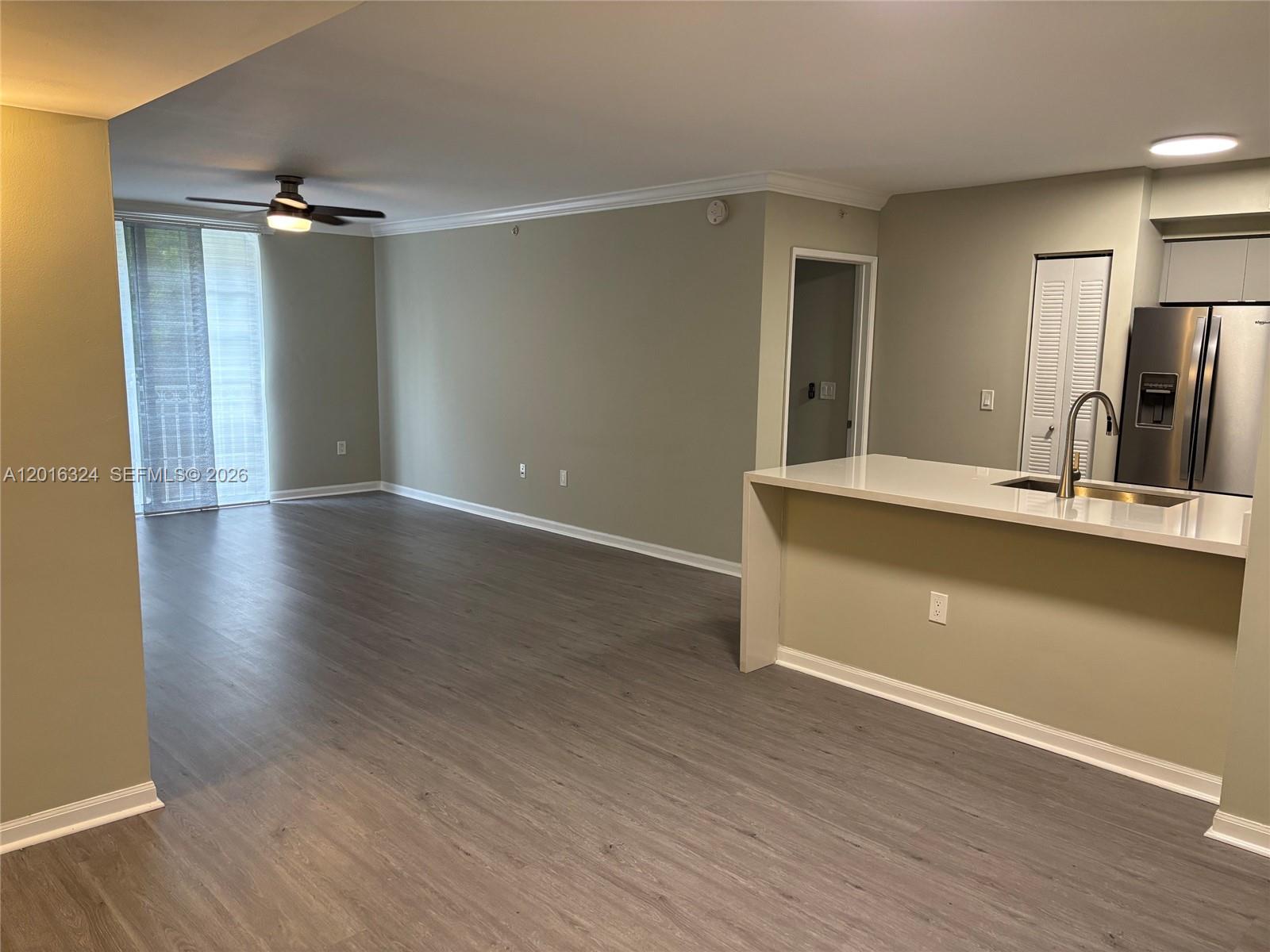 An open-concept living area features light gray walls, wood-look flooring, and a kitchen peninsula — 1900 Van Buren St # 201B, Hollywood FL 33020, HOLLYWOOD, FL