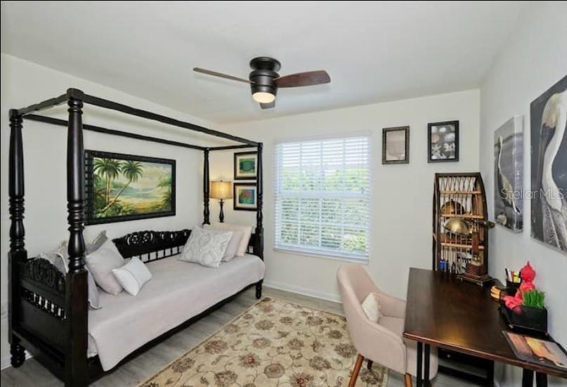 A bedroom features a dark wood canopy daybed, a desk with a chair, and a ceiling fan — 4105 RESIDENCE DRIVE UNIT 717, FORT MYERS, FL