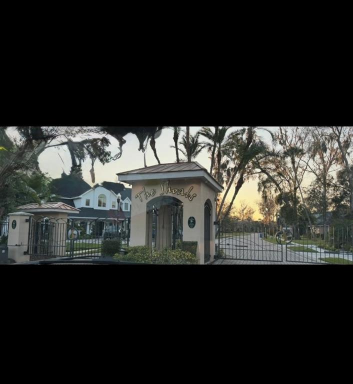 The gated entrance to a residential community features a stone monument sign reading The Shoals — 901 SHOALS LANDING DRIVE, BRANDON, FL