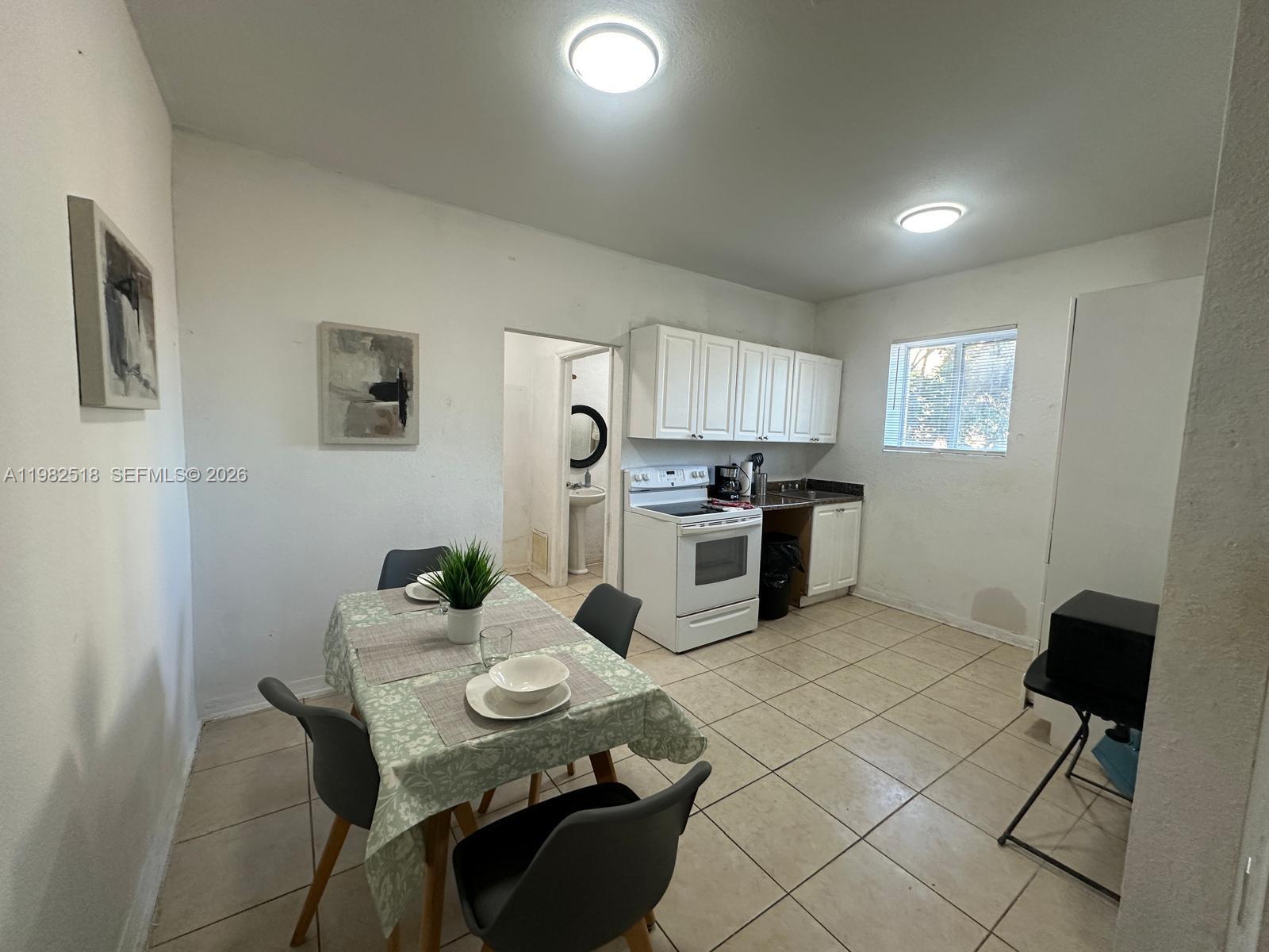 A kitchen and dining area features white cabinets, a white stove, and tiled flooring — 1021 NW 3rd St # 201, Miami FL 33128, MIAMI, FL