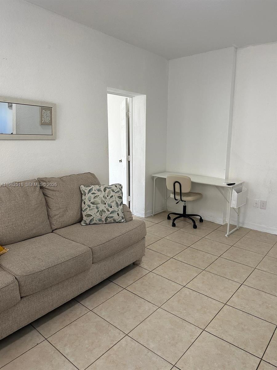 A living room features a beige sofa, a desk with a chair, and tiled flooring — 1021 NW 3rd St # 201, Miami FL 33128, MIAMI, FL