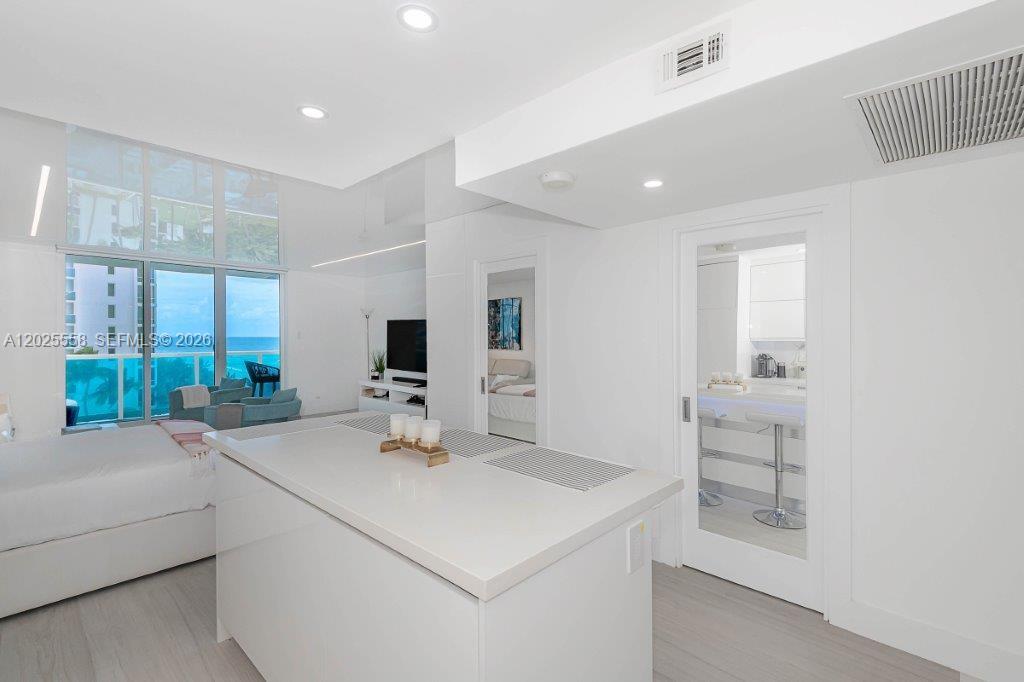 A modern kitchen island stands in a bright, white-toned living space with floor-to-ceiling windows — 2301 Collins Ave # 811, Miami Beach FL 33139, MIAMI BEACH, FL