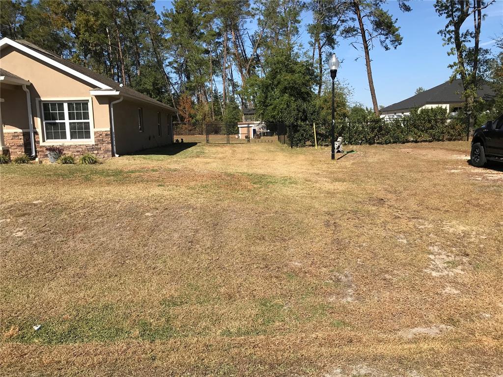 A side view of a house with a large, dry grassy yard and a fence — 4195 SW 114TH STREET, OCALA, FL
