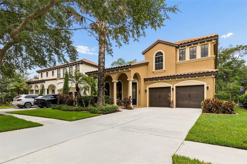 A two-story tan stucco house with a tile roof, arched entryway, and two-car garage — 20338 CHESTNUT GROVE DRIVE, TAMPA, FL