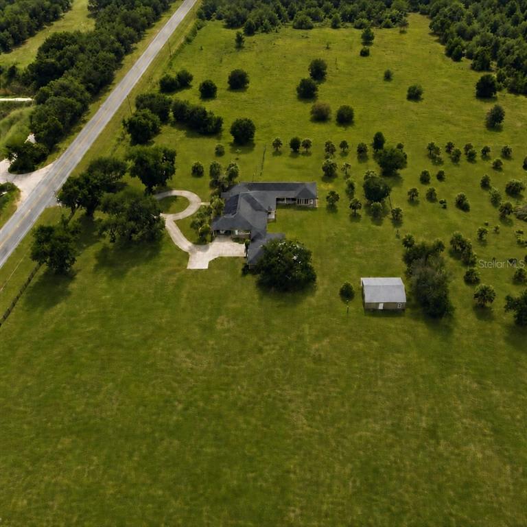 An aerial view shows a house with a driveway and a shed on rural land — 37180 COUNTY ROAD 452, GRAND ISLAND, FL
