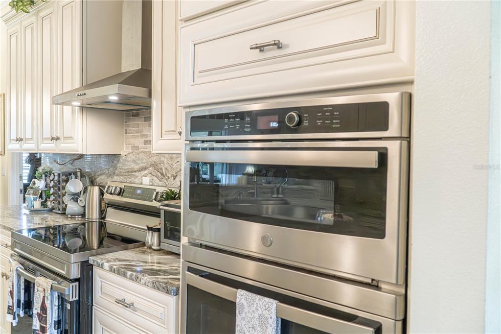 A kitchen features stainless steel appliances, white cabinetry, and a marble countertop — 37180 COUNTY ROAD 452, GRAND ISLAND, FL