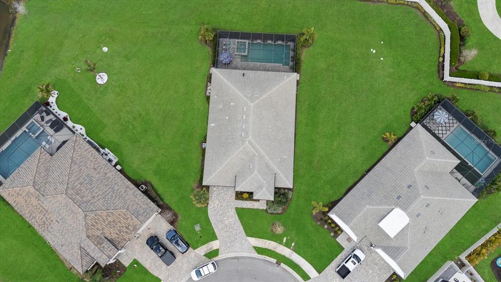 An aerial view shows three suburban houses with swimming pools and large green lawns — 4607 RAINWATER GLEN, BRADENTON, FL