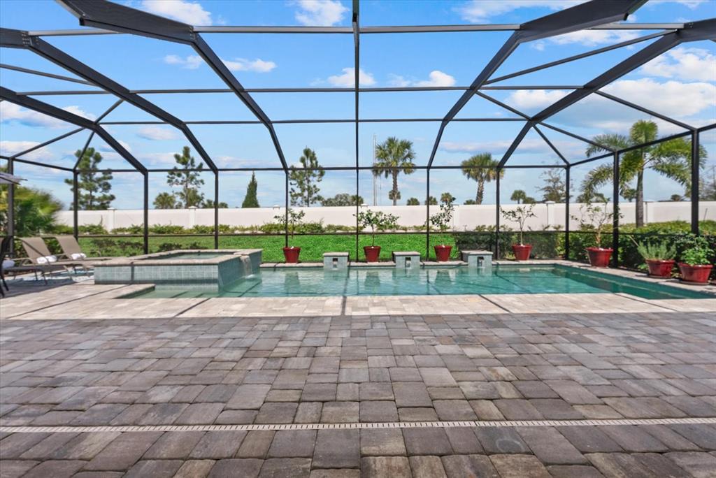 A screened-in patio features a rectangular swimming pool, a hot tub, and paver flooring — 4607 RAINWATER GLEN, BRADENTON, FL