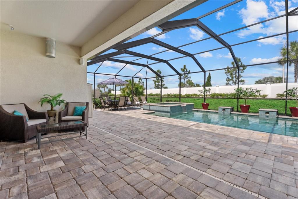 A covered patio features a paved deck, outdoor furniture, and a screened-in pool and spa — 4607 RAINWATER GLEN, BRADENTON, FL