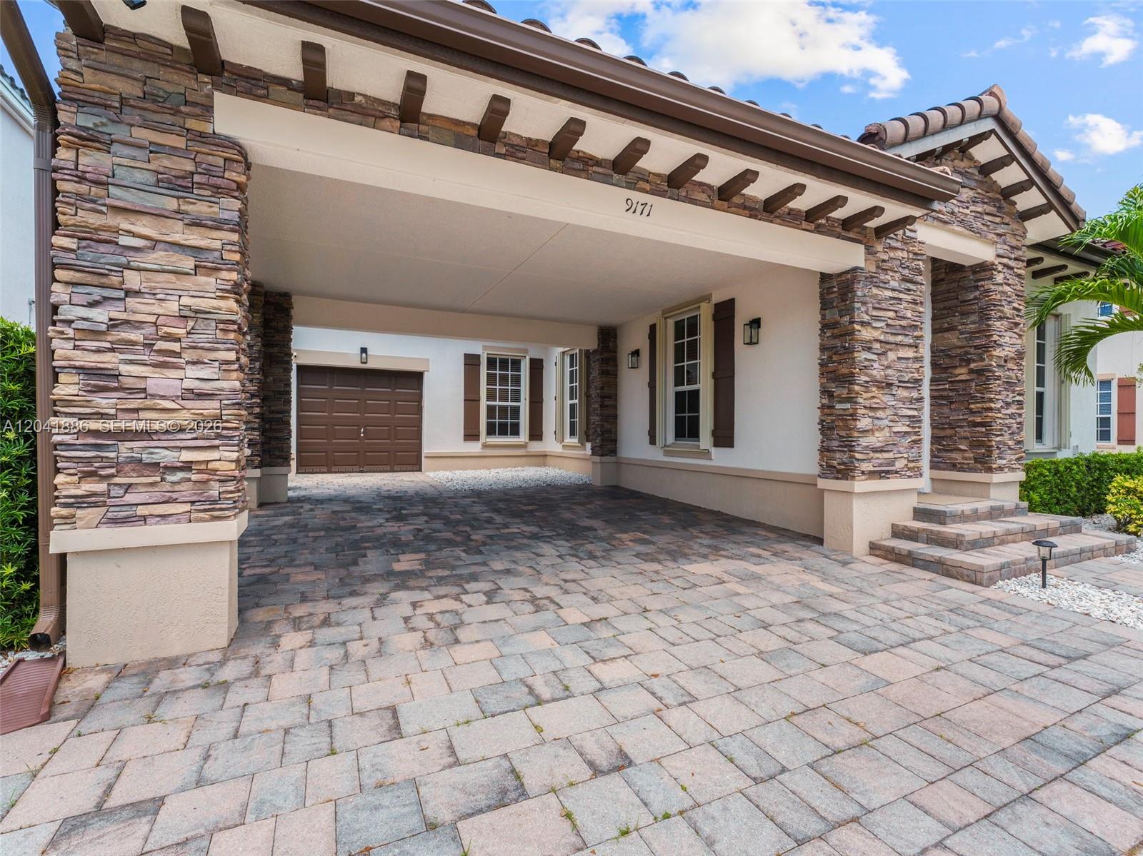 A paved driveway leads to a covered entryway and a brown garage door — 9171 SW 172nd Ave, Miami FL 33196, MIAMI, FL