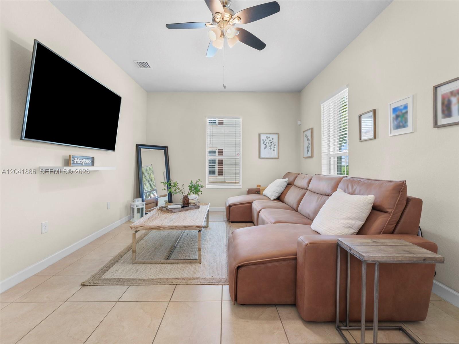 A living room features a brown leather sectional, a wooden coffee table, and a wall-mounted television — 9171 SW 172nd Ave, Miami FL 33196, MIAMI, FL
