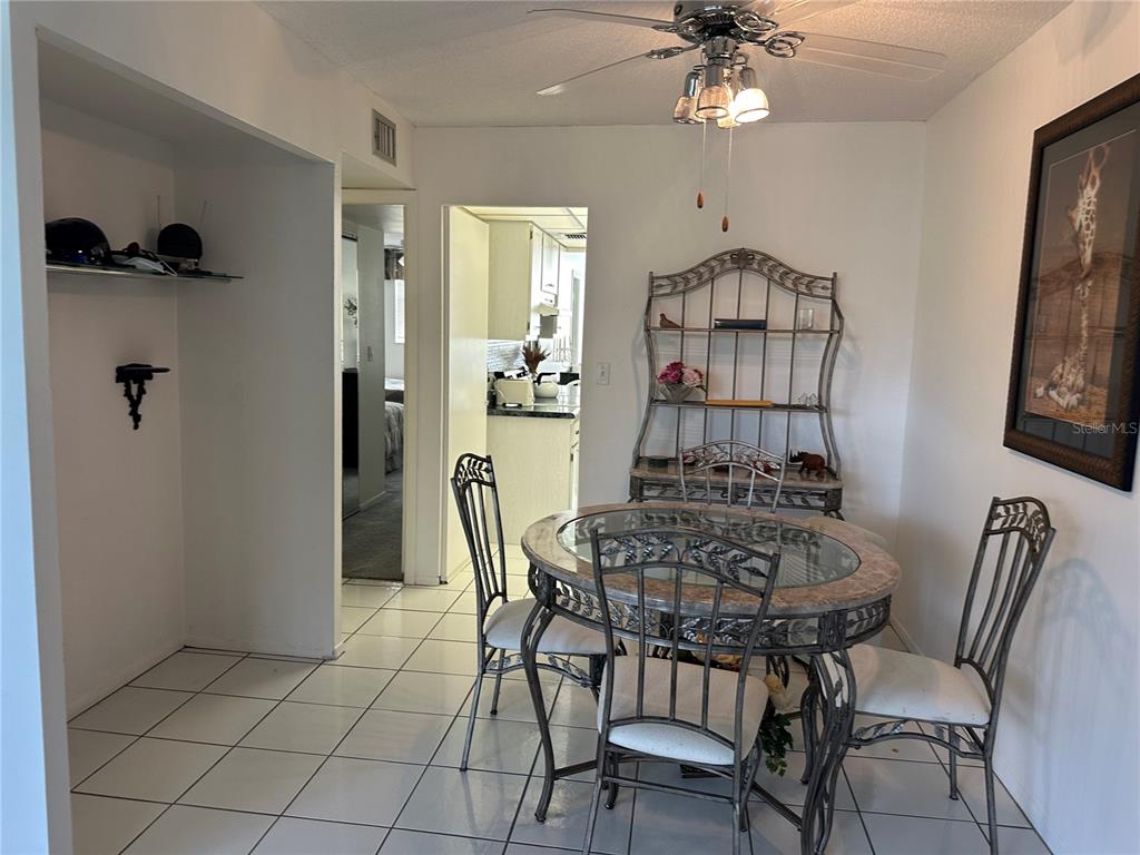 A dining room features a glass-topped table, metal chairs, a hutch, and tiled flooring — 4720 LOCUST STREET NE UNIT 314, ST PETERSBURG, FL
