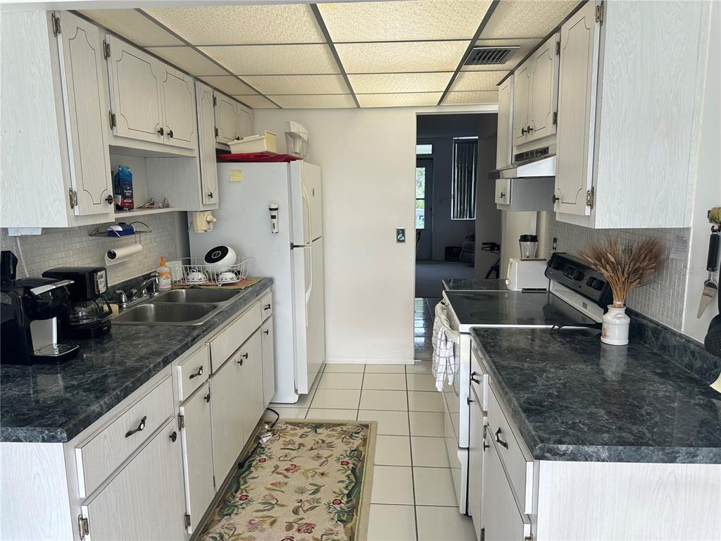 A kitchen features white cabinets, dark laminate countertops, white appliances, and a tiled floor — 4720 LOCUST STREET NE UNIT 314, ST PETERSBURG, FL