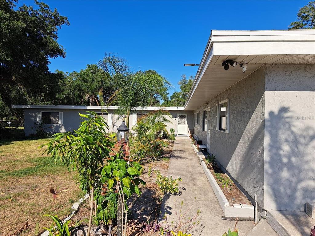 A concrete walkway leads along the side of a single-story house with a flat roof — 2814 N MARYLAND AVENUE, PLANT CITY, FL