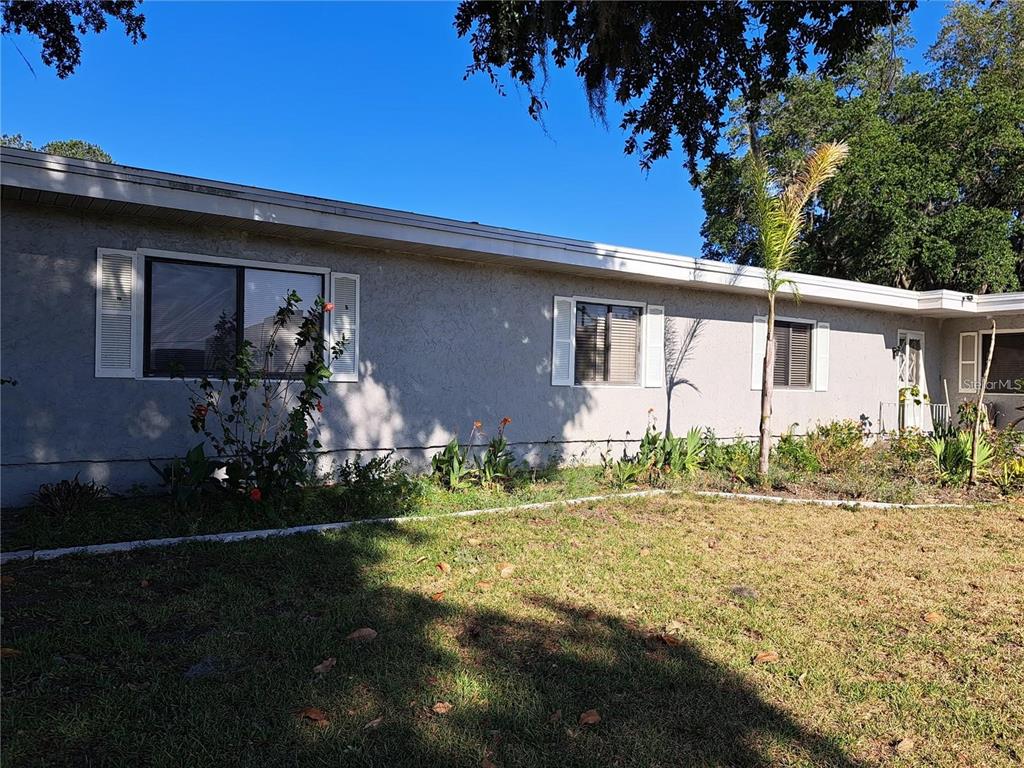 A single-story house exterior features gray stucco walls, white shutters, and a front lawn — 2814 N MARYLAND AVENUE, PLANT CITY, FL