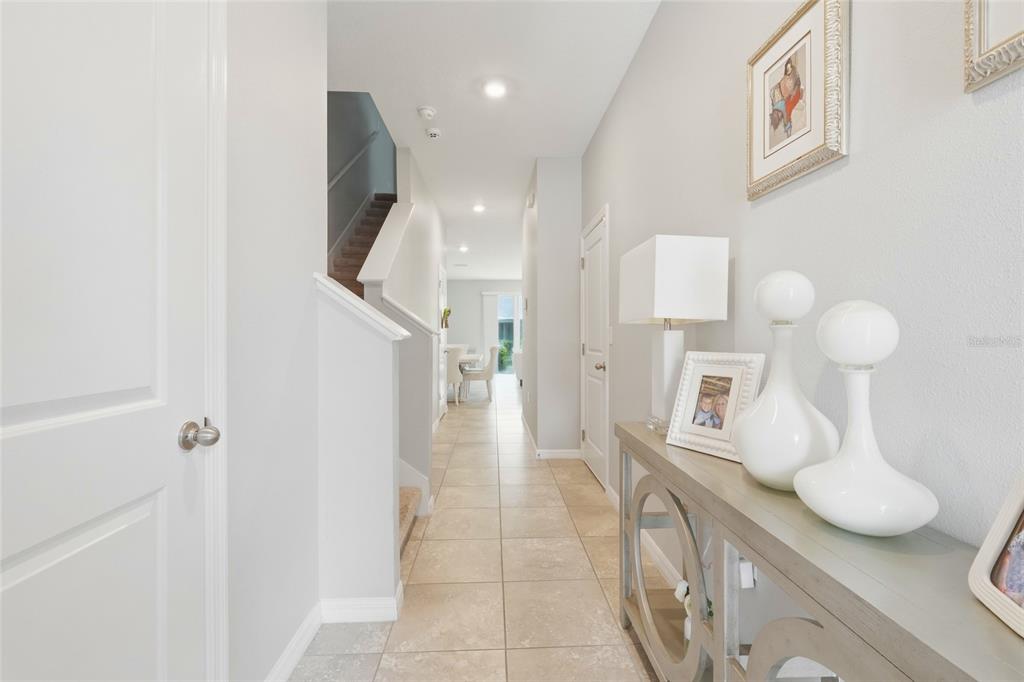 A tiled hallway leads past a staircase toward a dining area in a bright home — 6537 SERENITY FALL LANE, SARASOTA, FL