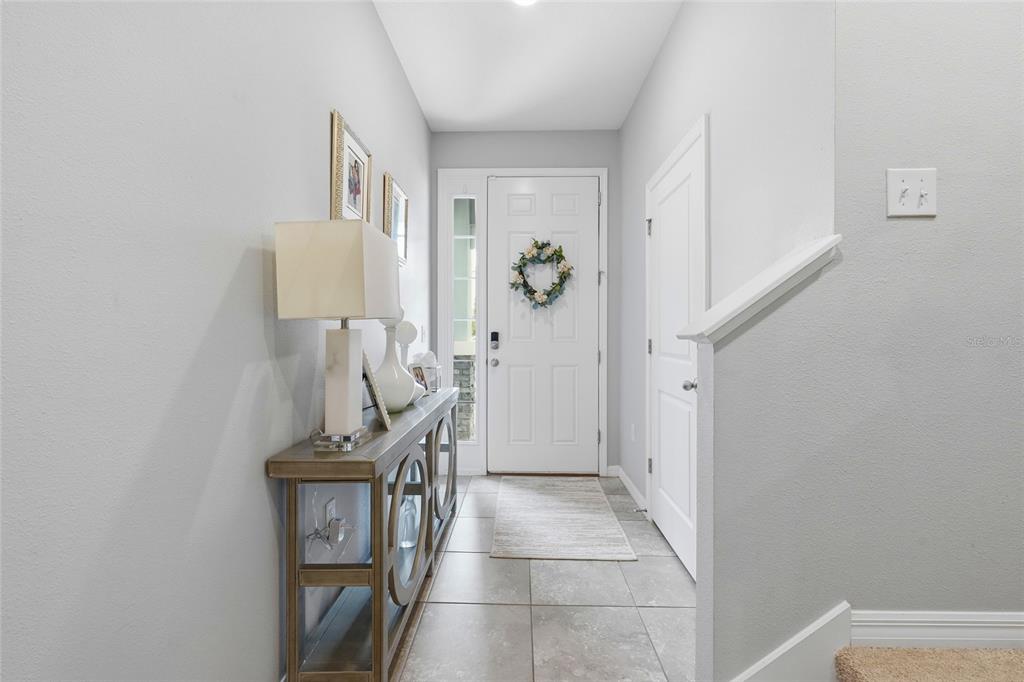 A bright entryway features a console table, tiled floor, and a white front door — 6537 SERENITY FALL LANE, SARASOTA, FL