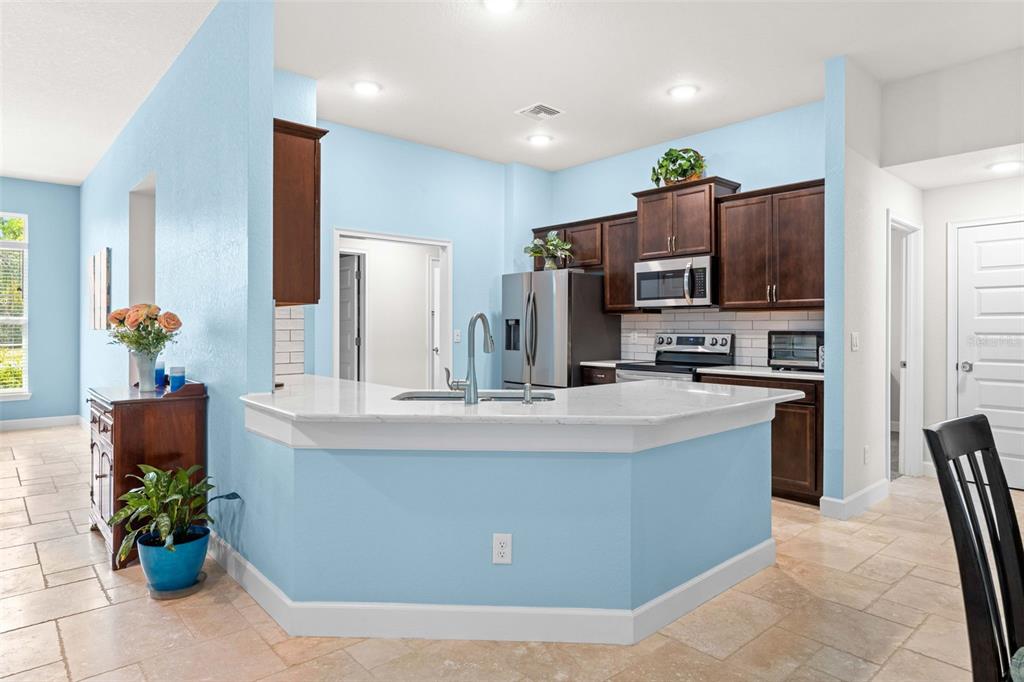 A kitchen with dark wood cabinets, white countertops, and light blue walls — 8 DAHLIA CIRCLE S, HOMOSASSA, FL