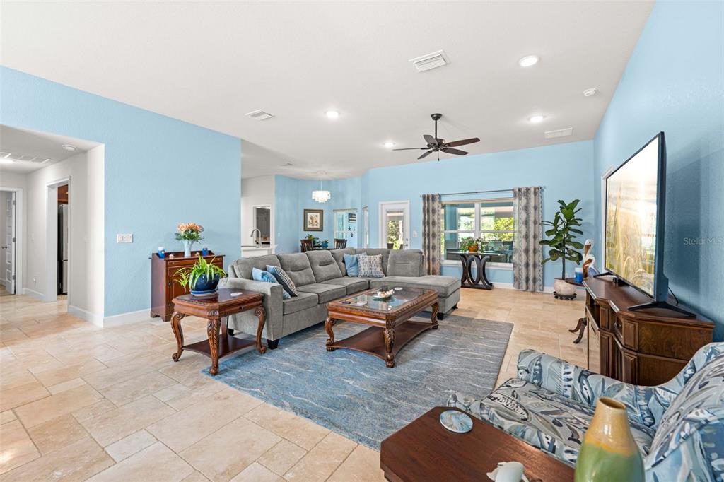 A living room features light blue walls, tile flooring, a gray sectional, and a television — 8 DAHLIA CIRCLE S, HOMOSASSA, FL