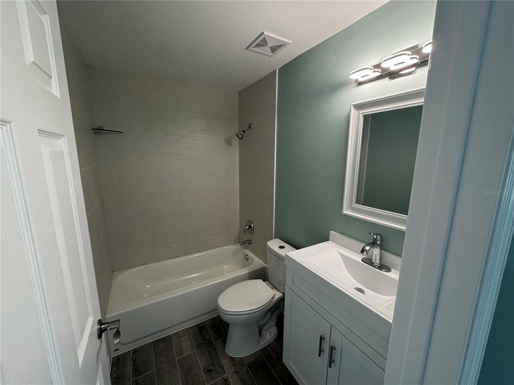 A bathroom features a white vanity, a toilet, and a bathtub with tiled walls — 1258 BARBARA DRIVE UNIT 202, VENICE, FL