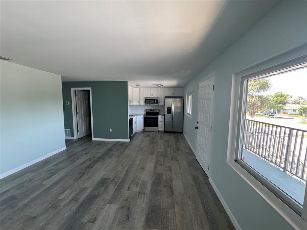 An open-concept kitchen and living area features gray wood-look flooring and a balcony view — 1258 BARBARA DRIVE UNIT 202, VENICE, FL