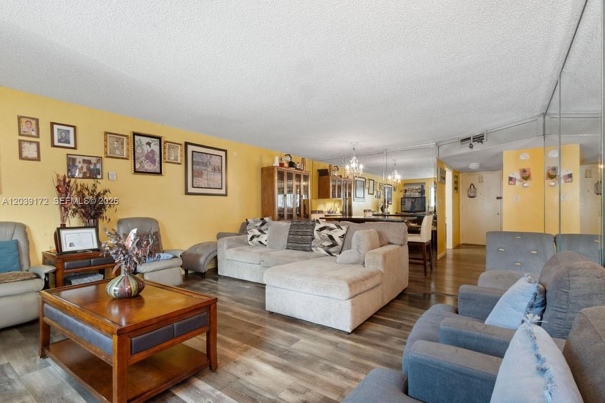 A living room with yellow walls, gray furniture, wood-look flooring, and a mirrored wall — 2271 NW 48th Ter # 112, Lauderhill FL 33313, LAUDERHILL, FL