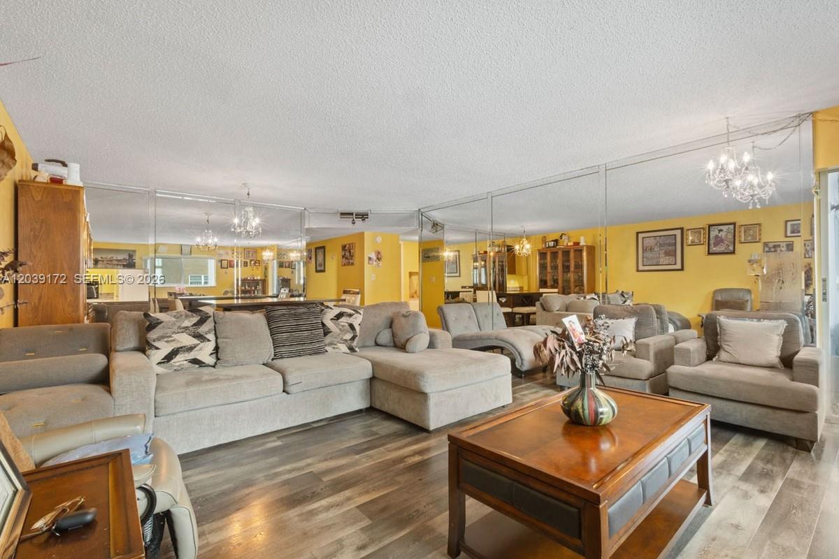 A living room features gray sectional seating, a wood coffee table, and mirrored walls — 2271 NW 48th Ter # 112, Lauderhill FL 33313, LAUDERHILL, FL