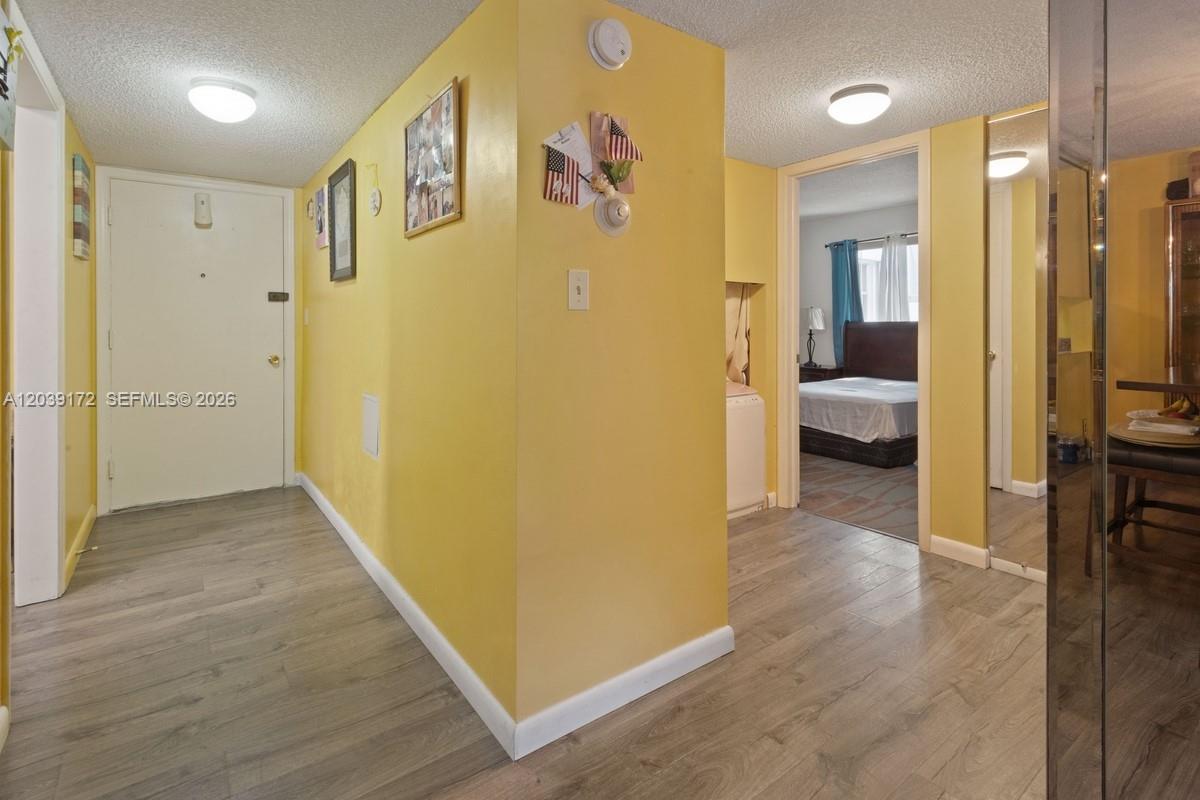 A yellow-walled entryway features wood-look flooring, a white door, and a view into a bedroom — 2271 NW 48th Ter # 112, Lauderhill FL 33313, LAUDERHILL, FL