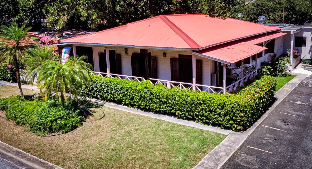 A white house with a red roof is surrounded by a hedge and palm trees — 127 KM 4.3 BO. QUEBRADAS AVENUE, GUAYANILLA, PR