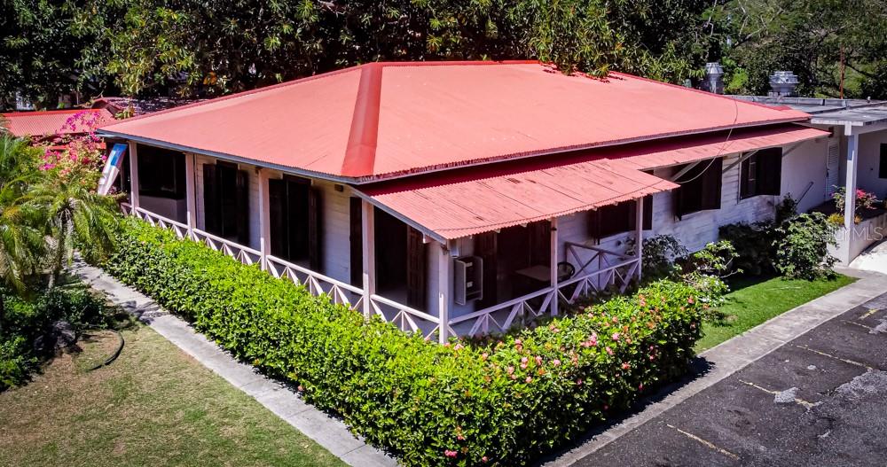 An exterior view of a white house with a red metal roof and wrap-around porch — 127 KM 4.3 BO. QUEBRADAS AVENUE, GUAYANILLA, PR