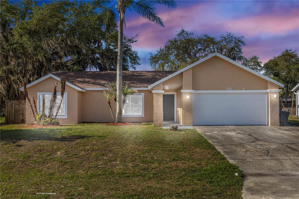 A single-story tan house with a two-car garage and a palm tree in the yard — 4845 HAWLEY ROAD, COCOA, FL