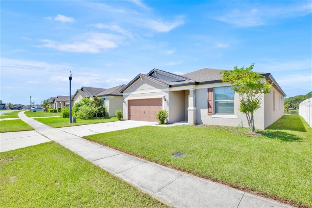 A single-story suburban house with a tan exterior, brown garage door, and a front lawn — 8755 RINDGE ROAD, POLK CITY, FL