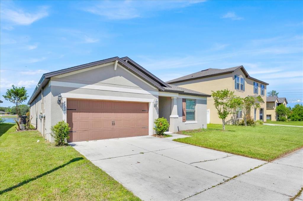 A single-story house with a brown garage door and a concrete driveway under a blue sky — 8755 RINDGE ROAD, POLK CITY, FL
