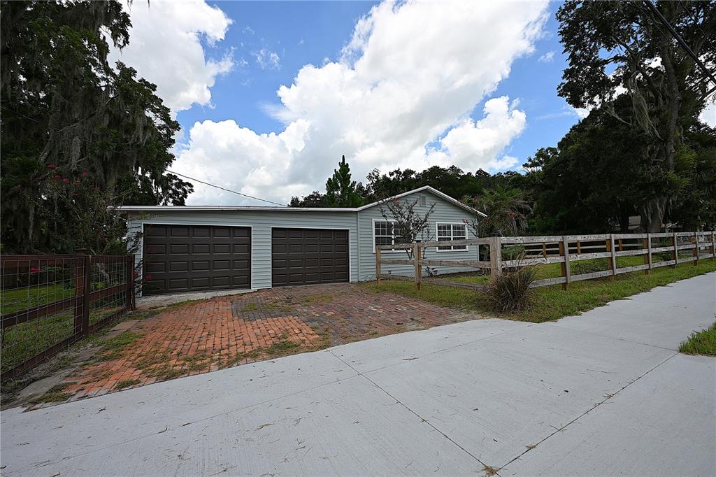 A light blue house with a two-car garage and a brick driveway behind a fence — 3958 2ND STREET NW, LAKELAND, FL