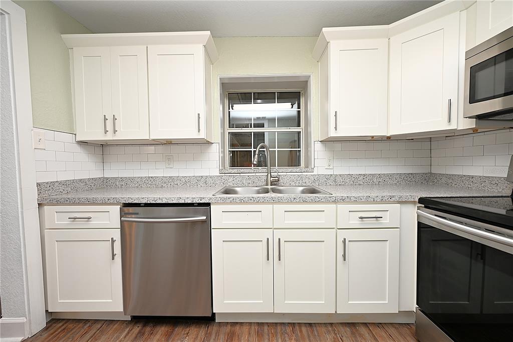 A kitchen with white cabinets, stainless steel appliances, granite countertops, and a subway tile backsplash — 3958 2ND STREET NW, LAKELAND, FL