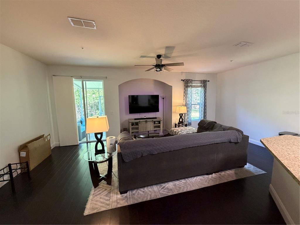 A living room features dark wood floors, a sectional sofa, and a television in an alcove — 15353 OAK APPLE COURT, WINTER GARDEN, FL
