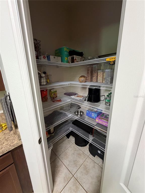 A walk-in pantry features white wire shelving, tiled flooring, and various food storage containers — 15353 OAK APPLE COURT, WINTER GARDEN, FL