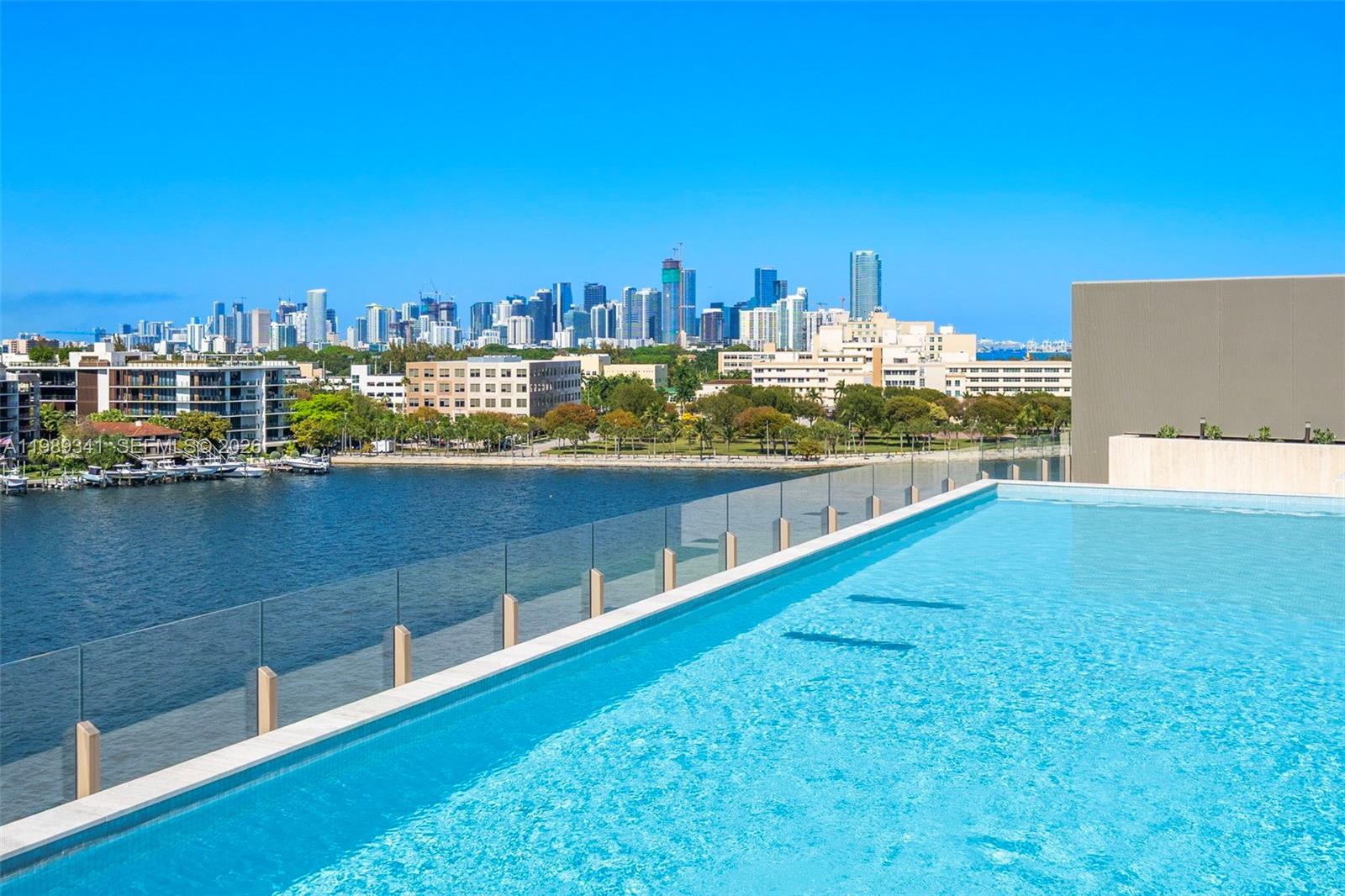 An infinity pool overlooks a bay with a city skyline in the background — 5 Grove Isle Dr, Coconut Grove FL 33131, COCONUT GROVE, FL