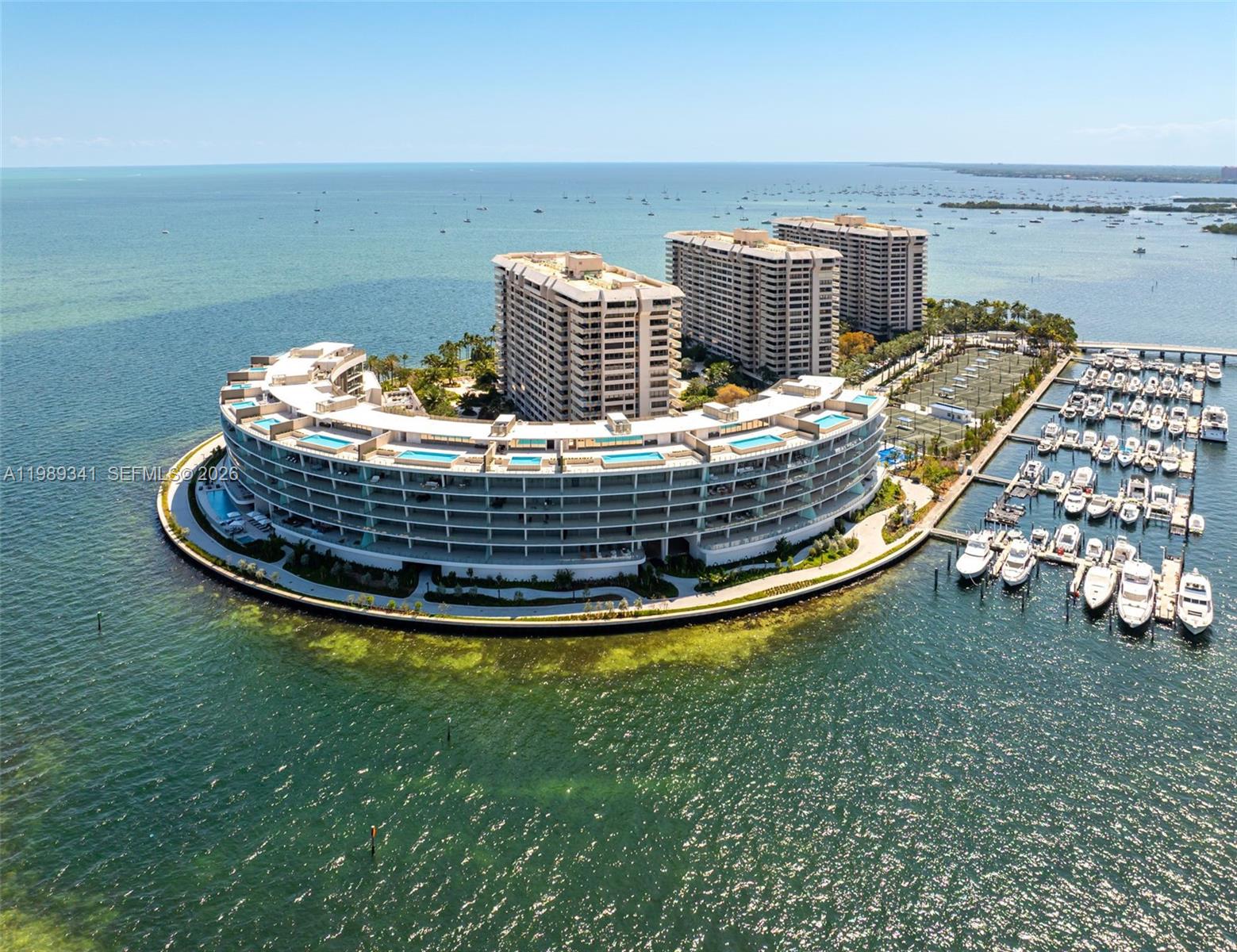 An aerial view shows a curved residential building complex with a marina on the water — 5 Grove Isle Dr, Coconut Grove FL 33131, COCONUT GROVE, FL