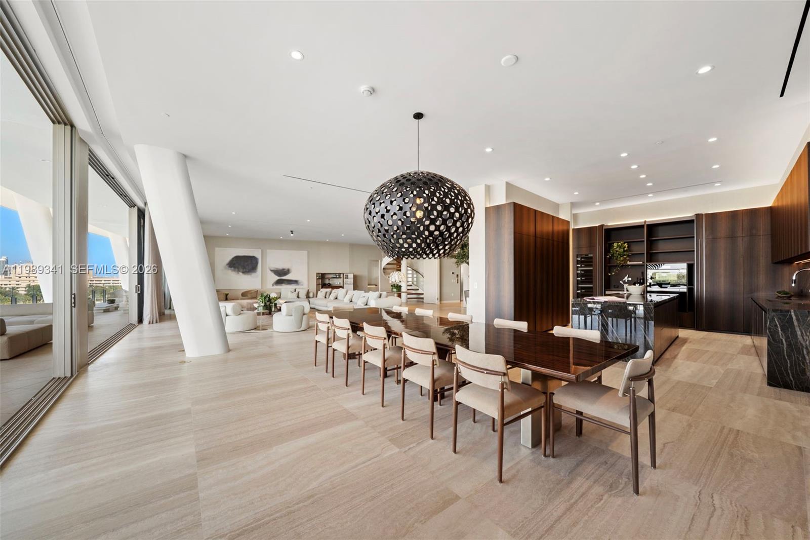 A modern open-plan dining and kitchen area features a large pendant light and stone flooring — 5 Grove Isle Dr, Coconut Grove FL 33131, COCONUT GROVE, FL