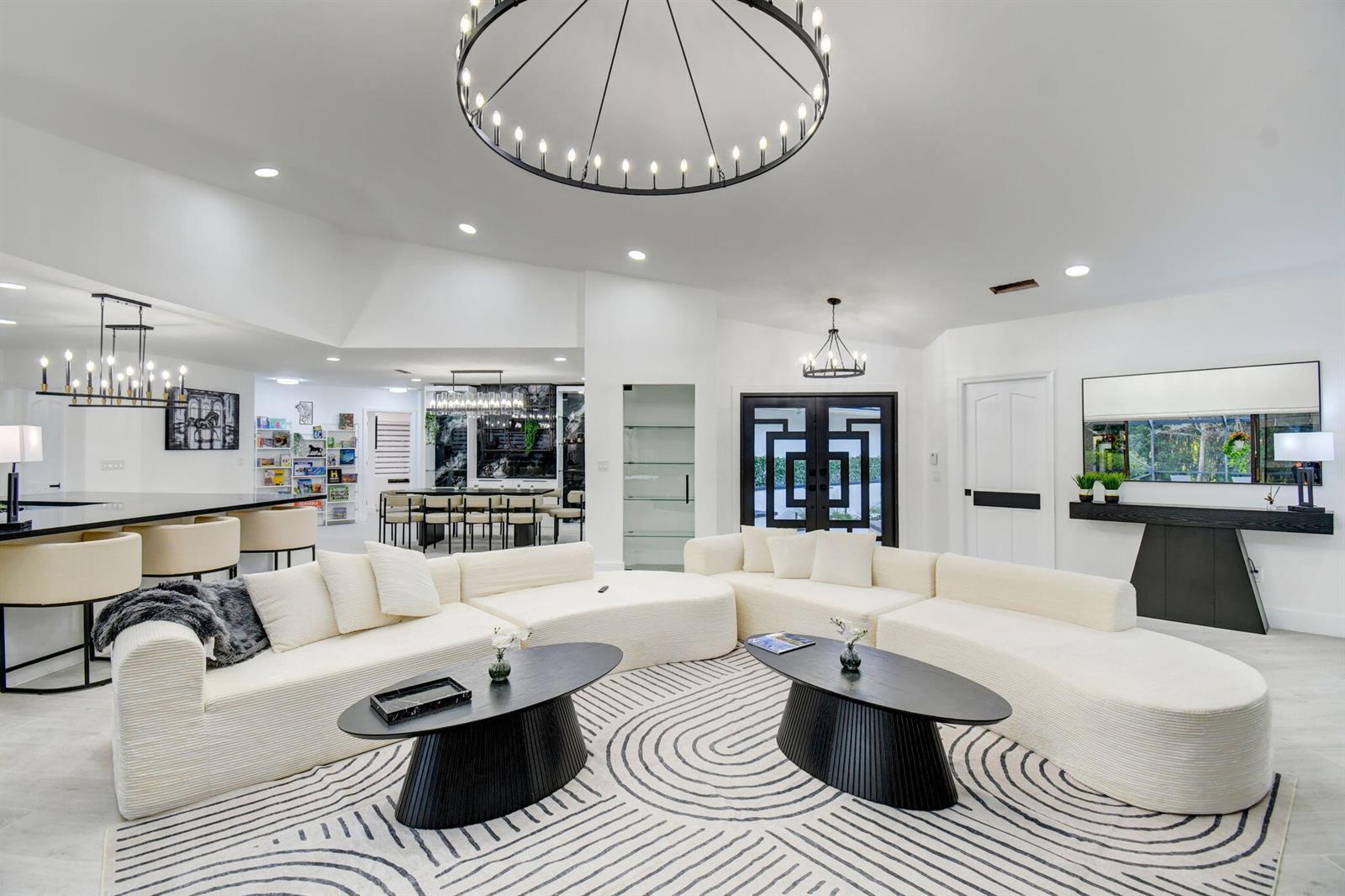 A spacious living room features a large white sectional, two black coffee tables, and a chandelier — 13302 Doubletree Circle, Wellington FL 33414, WELLINGTON, FL