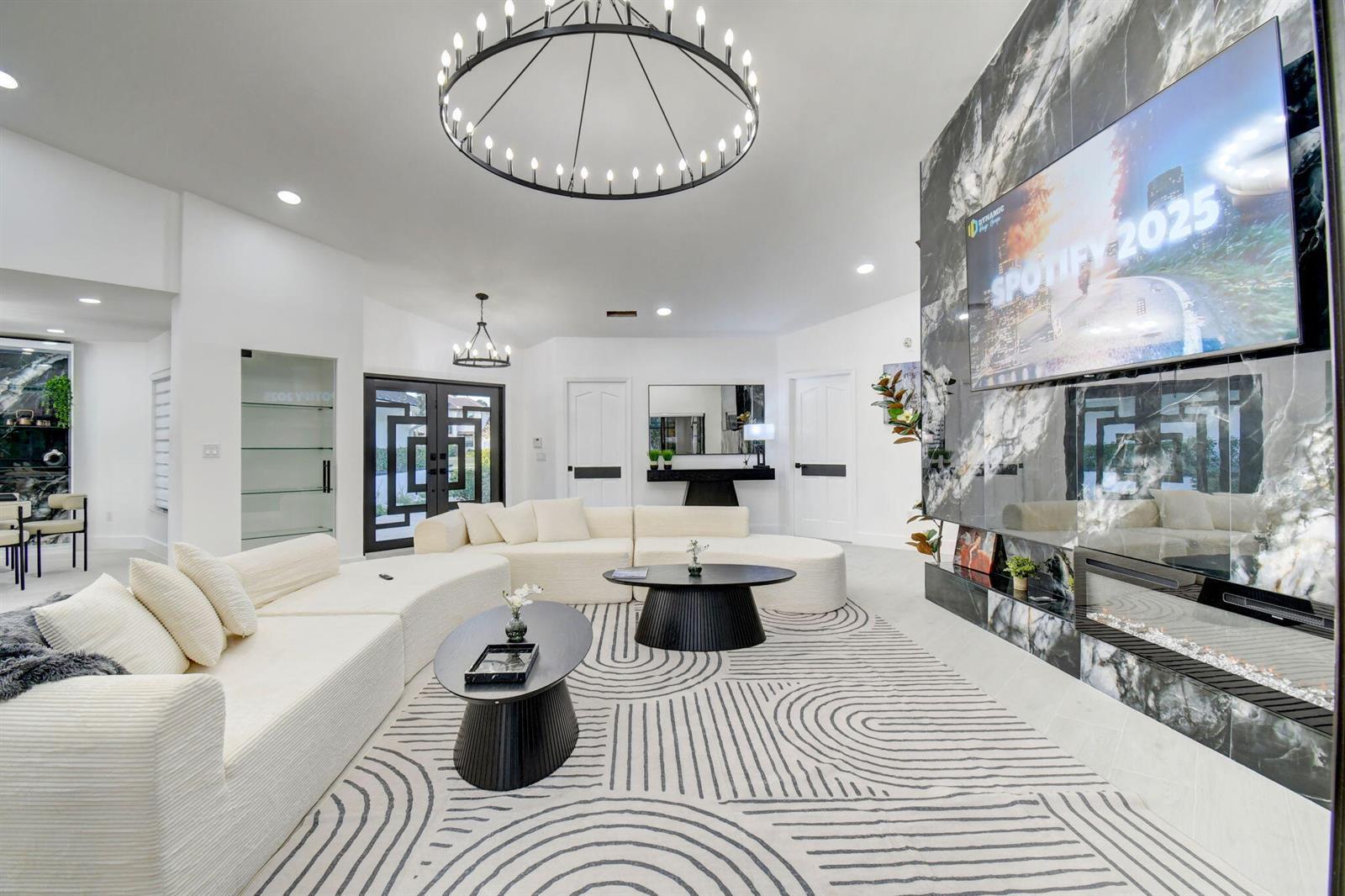 A modern living room features a large white sectional, two black coffee tables, and marble fireplace — 13302 Doubletree Circle, Wellington FL 33414, WELLINGTON, FL
