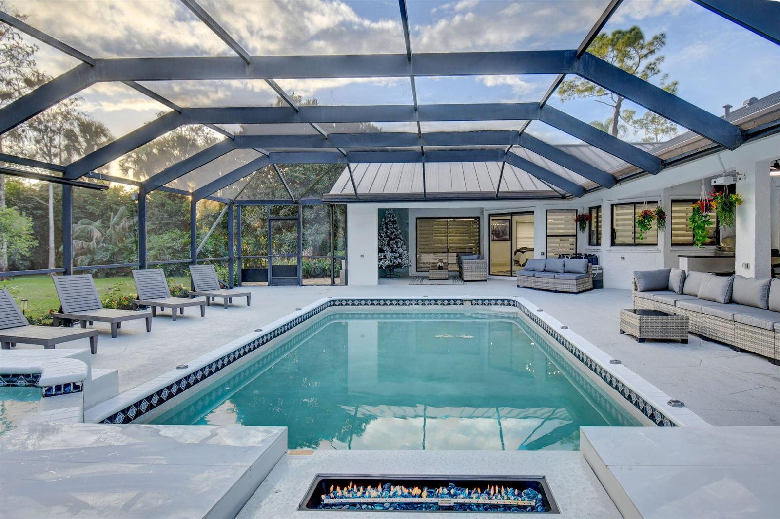 A screened-in patio features a rectangular swimming pool, a fire pit, and outdoor lounge furniture — 13302 Doubletree Circle, Wellington FL 33414, WELLINGTON, FL
