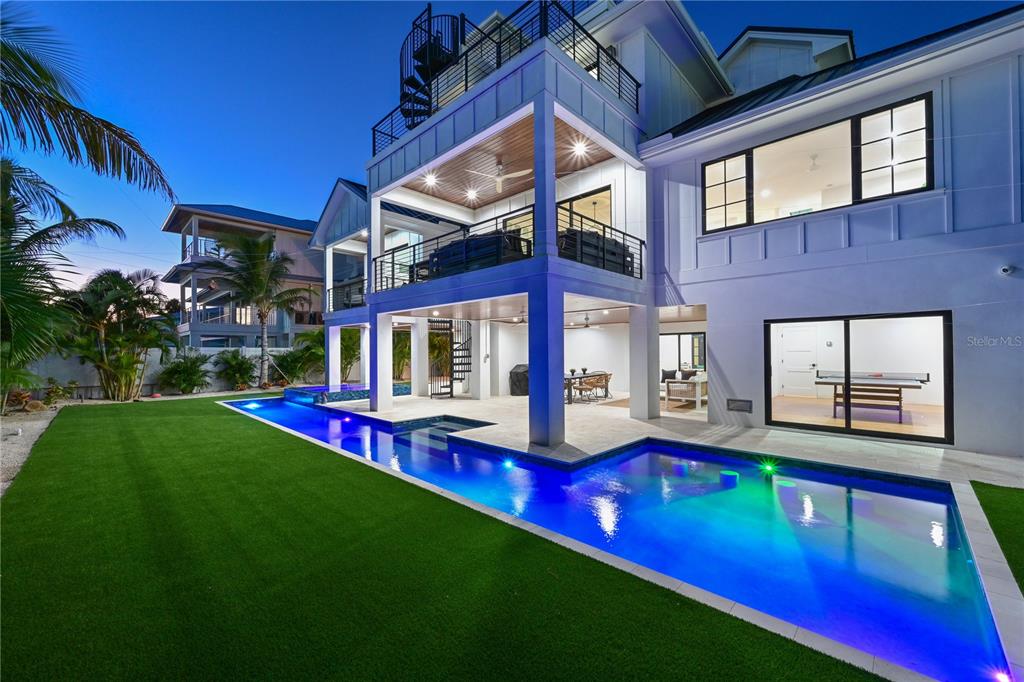 A modern two-story house features a long lap pool, artificial turf, and a spiral staircase — 305 55TH STREET, HOLMES BEACH, FL