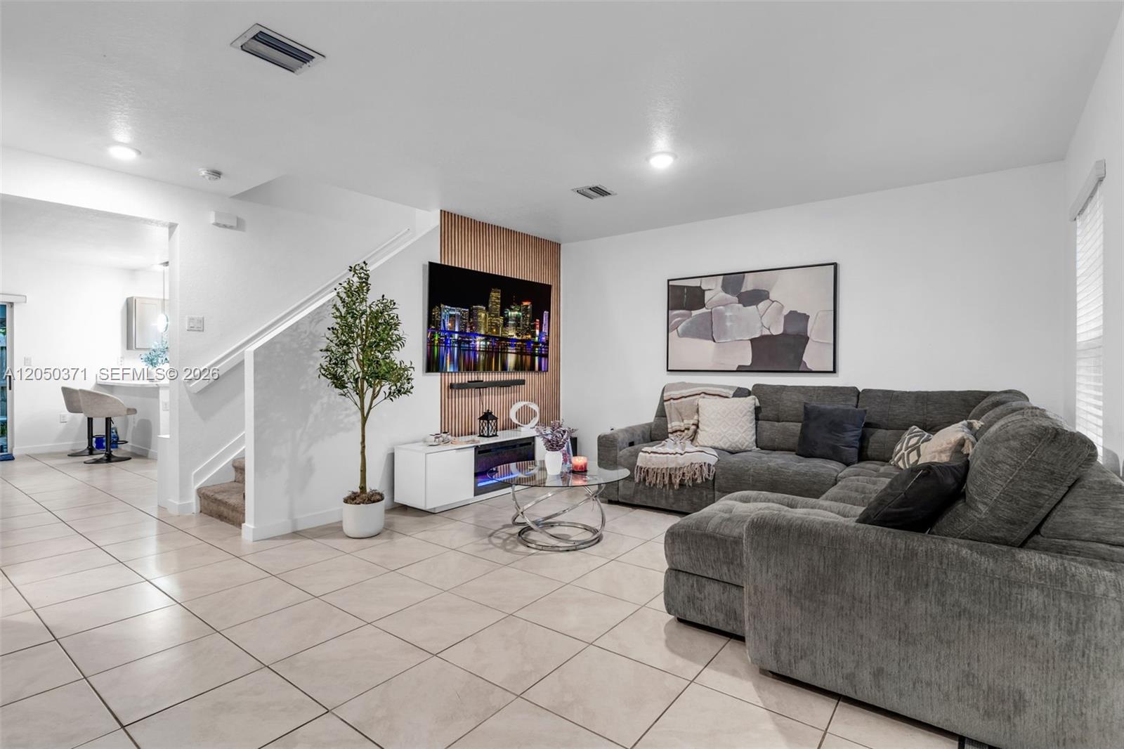 A living room features a grey sectional sofa, a wall-mounted television, and tiled flooring — 533 NE 5th Pl, Florida City FL 33034, FLORIDA CITY, FL