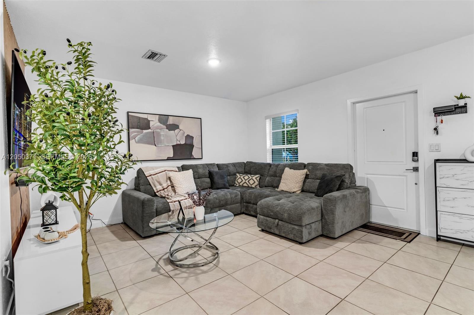 A living room features a grey sectional sofa, a glass coffee table, and tile flooring — 533 NE 5th Pl, Florida City FL 33034, FLORIDA CITY, FL