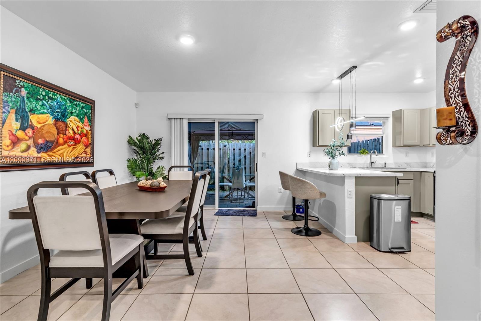 A dining area and kitchen feature tile floors, a wooden table, and sliding glass doors — 533 NE 5th Pl, Florida City FL 33034, FLORIDA CITY, FL