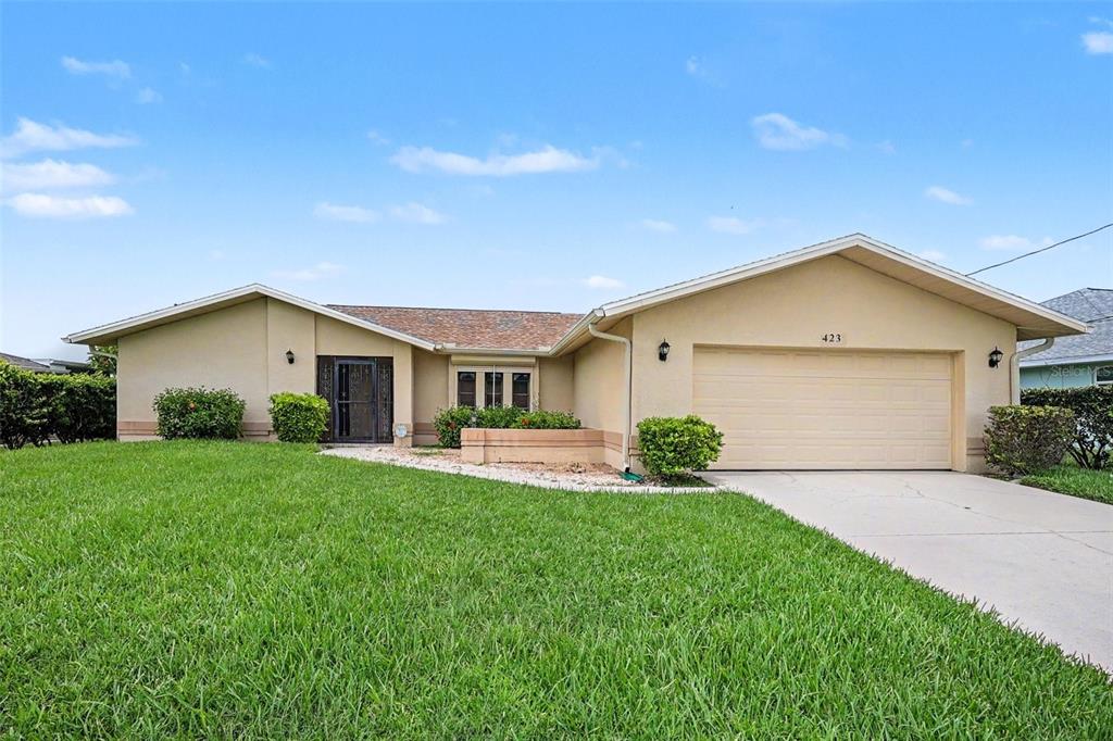 A single-story house with a beige exterior, a two-car garage, and a manicured front lawn — 423 SW 12TH STREET, CAPE CORAL, FL