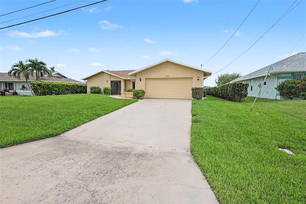 A single-story house with a beige exterior, a two-car garage, and a concrete driveway — 423 SW 12TH STREET, CAPE CORAL, FL