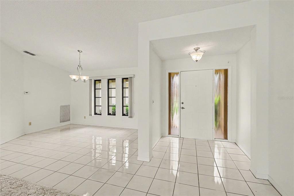 An entryway and dining area with white tile floors, a chandelier, and a front door — 423 SW 12TH STREET, CAPE CORAL, FL